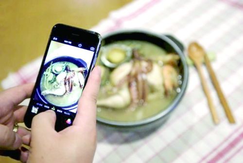一名韓國男子用手機拍攝自己親手做的參雞湯。